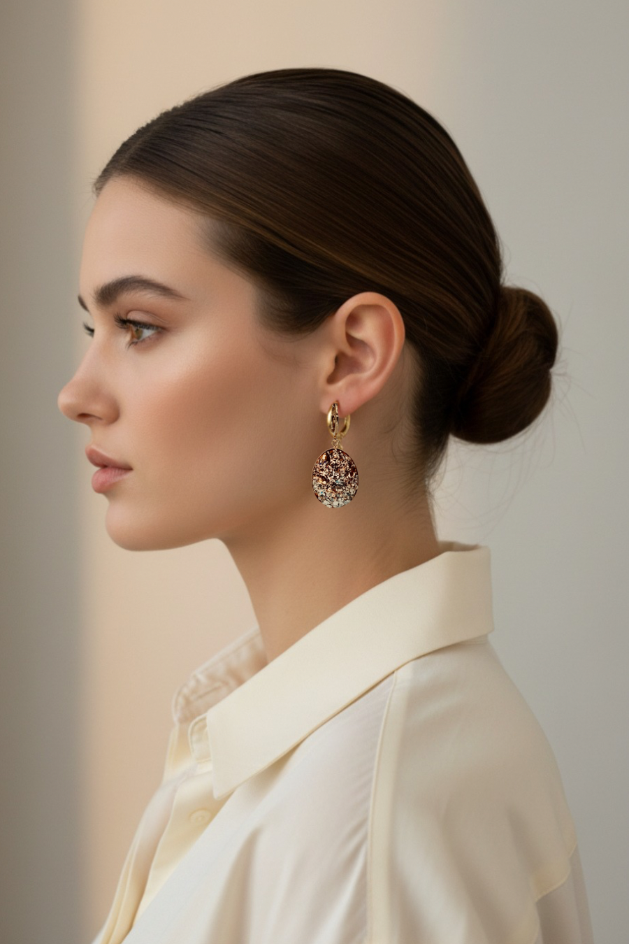 Woman wearing gold earrings with a neutral background